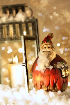 Brightly lit lantern in the snow with little Santa