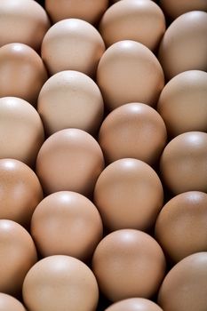 A background with lots of brown chicken eggs, from above.