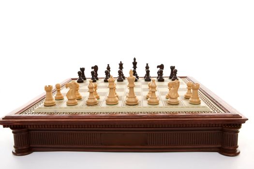 A chess gameboard with playing pieces ready. . Each player has 16 playing pieces and white always plays first.