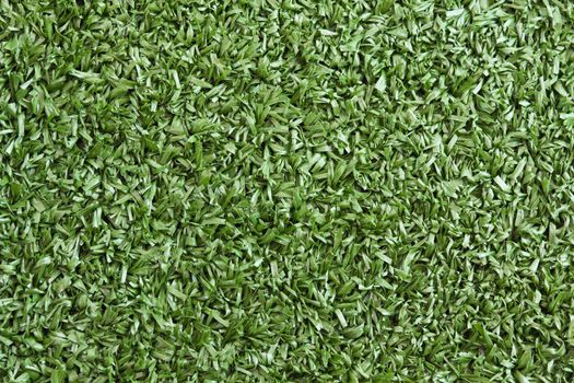 Background texture with fake grass in a public children playground, top view