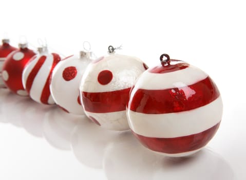 A selection of red and white Christmas baubles on a white background.  Focus is to first bauble.  Space for copy.