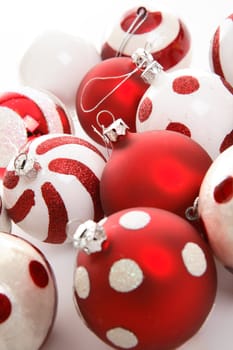 Various Christmas baublesin red and white theme colours sit  on a white background.  Focus to centre balls.