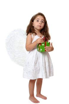 Angel girl wearing white embroidered dress and feathered wings is holding a red and green Christmas or brithday  present.