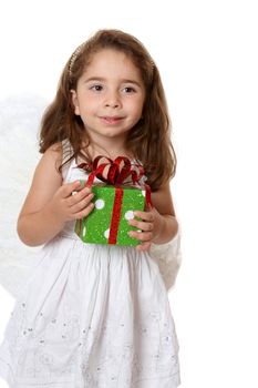 Beautiful little girl wearing a white dress and wings is holding a present.