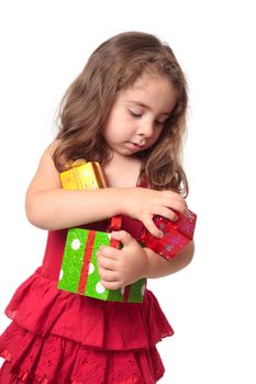 Little girl holding some Christmas presents in her arms.