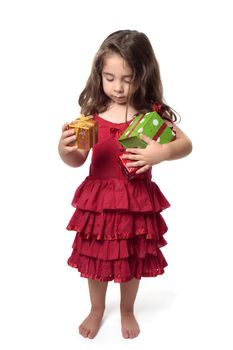 Young girl in pretty red dress holding an armful of red, green and gold gifts.