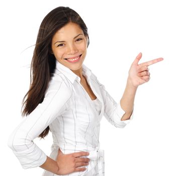 Smiling and confident woman in white pointing at your product while looking at the camera. Isolated on white background.Beautiful mixed asian / caucasian model.