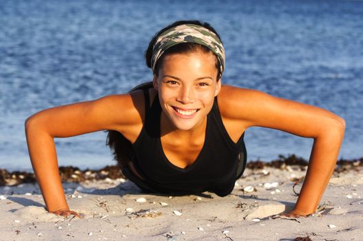 Attractive woman doing push-ups on the beach.