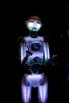 A neon colored glowing robot on display at the Telus Science musium in Edmonton stretching out its hands to the crowd