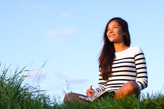 Woman studying outside in evening light with copy space. Beautiful mixed asian / caucasian woman.