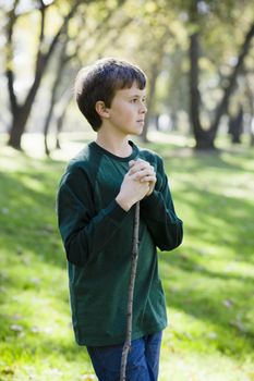Profile of Young Boy Standing With Stick in a Park