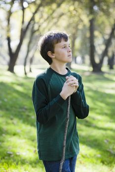 Profile of Young Boy Standing With Stick in a Park