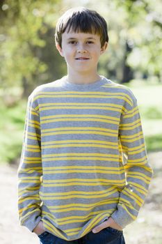 Cute Young Boy Standing Outdoors With Hands in Pockets