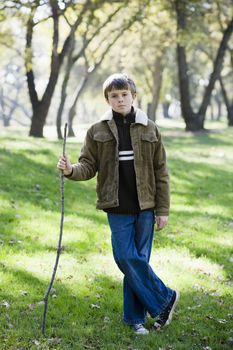 Young Boy Standing With Stick Looking Directly To The Camera