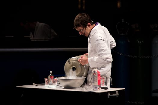 A scientist conducting an experiment to make ice cream out of cream using liquid nitrogen which is forming a white smoke of cold gas as it vaporizes.