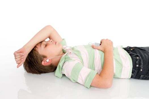 A young boy lying down listening to music on a digital portable mp3 player.