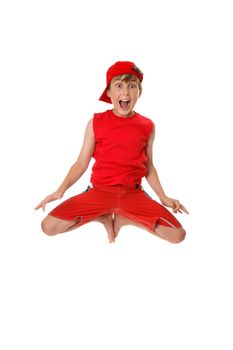 Thrilled boy jumps off the ground with feet in tight to his body.