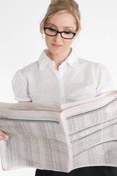 A businesswoman reading the financial newspaper.  Please note newsprint has been artificially blurred to render company names illegible.