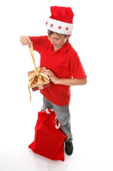 A boy, sack of toys at his feet,  opens a Christmas  present