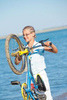 beautiful young girl standing with her bicycle. the background sea