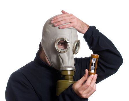 A man wearing a gas mask is looking at an hour glass realizing he is out of time, isolated against a white background