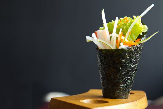 Japanese food, California hand roll hold in a wooden fixture