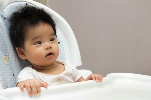 Portrait of a little Asian baby girl sits on a high chair