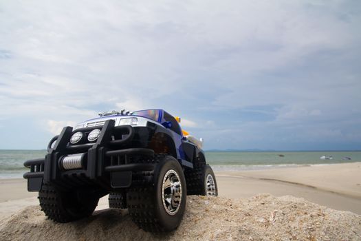Radio control monster truck on a beach against blue sky
