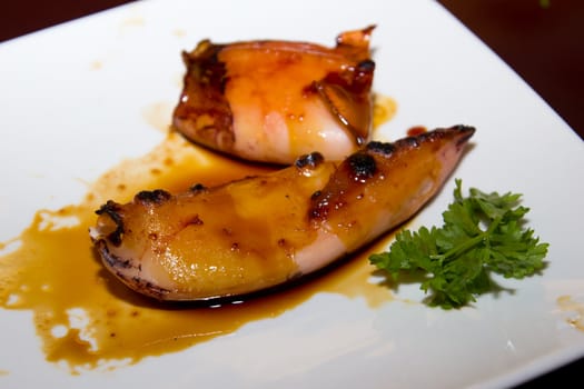 Grilled Japanese squid with black sauce on a white plate