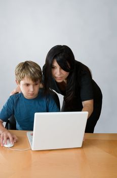 An adult assists a child using a laptop computer.