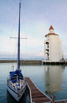 Beautiful yacht docked at jetty with a lighthouse behind