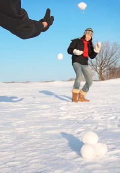 Snowball fight - winter fun. Couple throwing snowballs at each other.