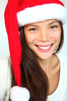  Christmas girl in a Santa hat smiling. Very beautiful mixed asian / caucasian model. Isolated on white background.