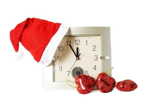 Santa cap on clock and some Christmas decoration over white