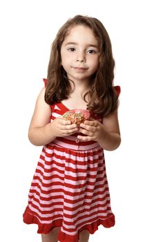 Young child holding a pink iced doughnet.   She is wearing a pink and red striped dress with little pink  heart buttons.