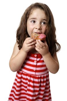 Young girl in a pink and red dressed is eating a pink iced doughnut.