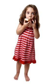 Little girl in a pink and red striped dress is holding and eating a doughnut with two hands.