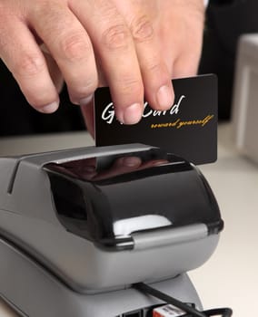 Man swiping a gift card, credit or debit card.   Original card front has been replaced including text with my own.   Focus to hand and card.  Shallow dof.  This could be a sales person or a customer.  You could also replace this with your own store card or bankcard.