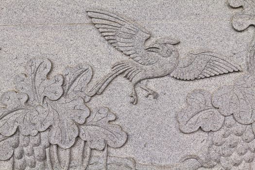 Bird carved on stone wall in chinese temple Thailand