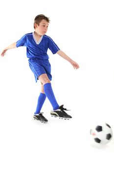 A boy kicks a soccer ball.   Motion in ball and kicking leg.