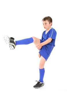 A boy dressed in soccer uniform  kicking.  Focus to face.  Motion in moving leg and arm.