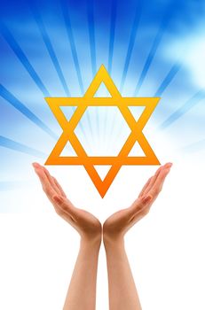 Hand holding a Jewish Star on cloud background.