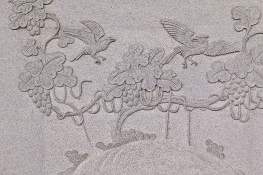 Bird carved on stone wall in chinese temple Thailand