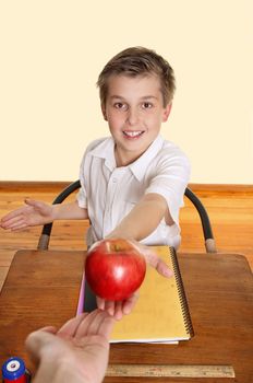 A schoolboy hands his teacher a red apple.