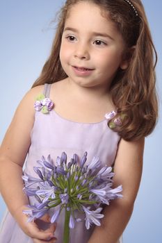 Sweet pretty young girl holding a large agapanthus liily flower.
