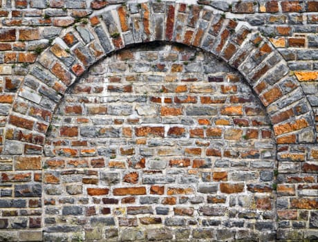 Old bricks stonewall from cut out rocks with arched brickwork