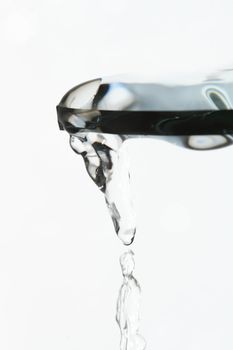 Piece of glass with flowing water on white background