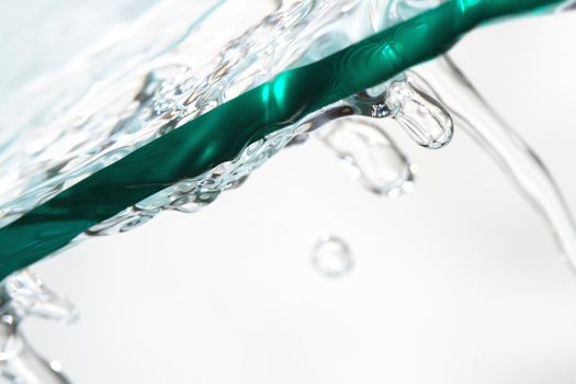 Piece of glass with flowing water on white background