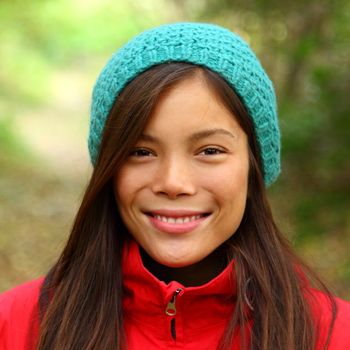 Woman smiling outdoors in Autumn. Beautiful mixed asian / caucasian woman walking in the forest on a fall day.