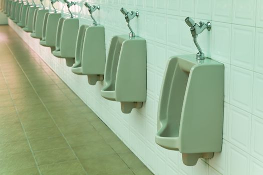 A row of urinals in tiled wall in a public restroom